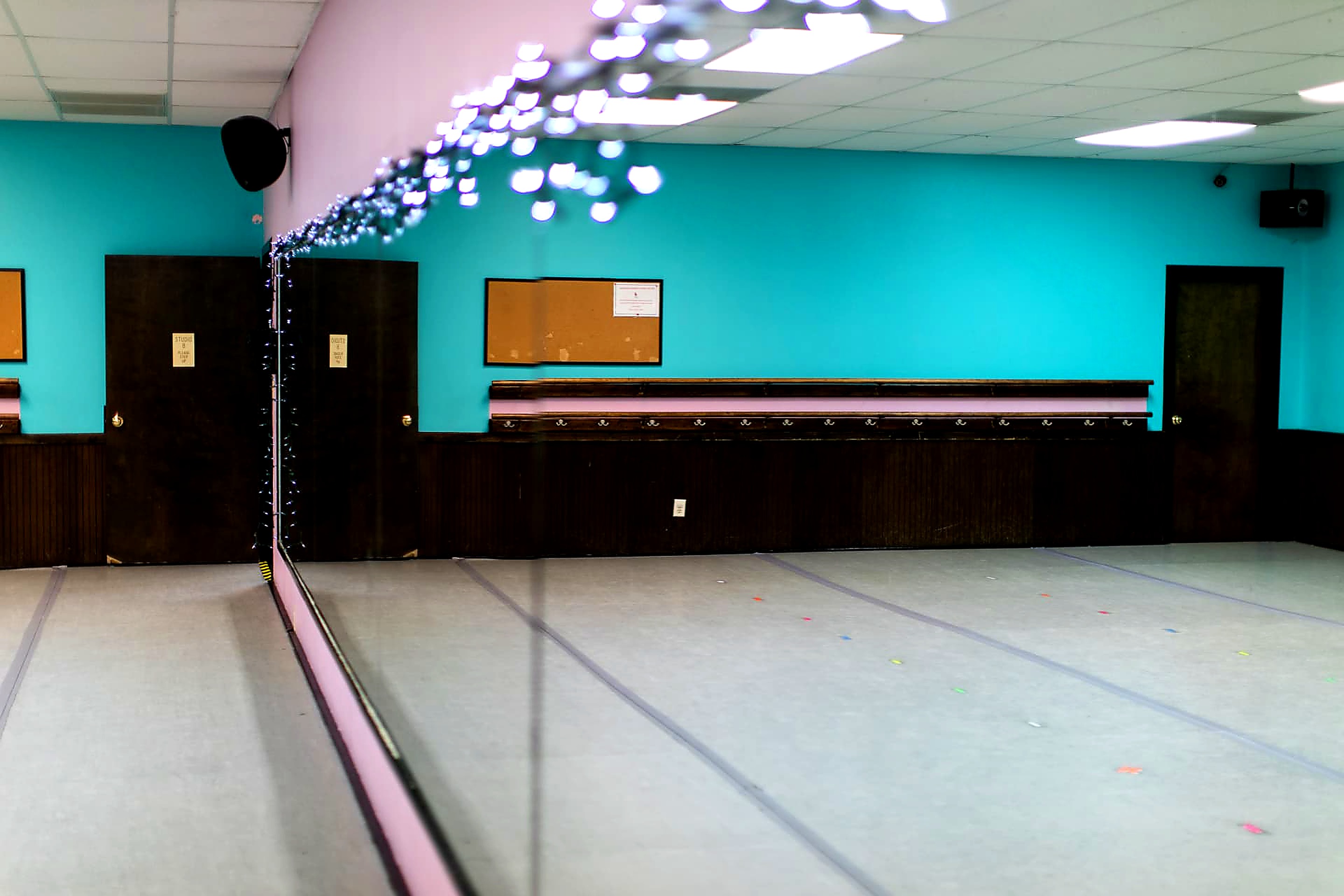 Teal studio with mirrored wall, barres and string lights