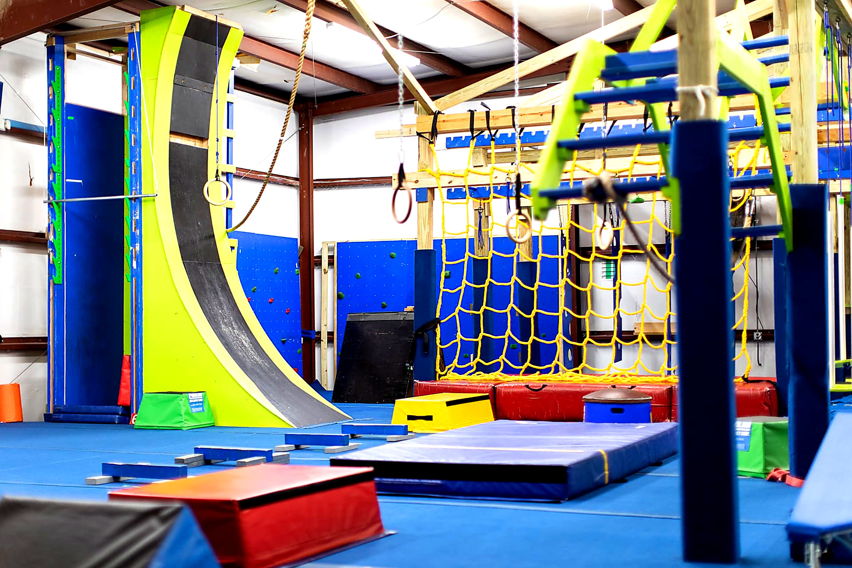 Warped wall, climbing holds and cargo net in the Ninja Warrior gym