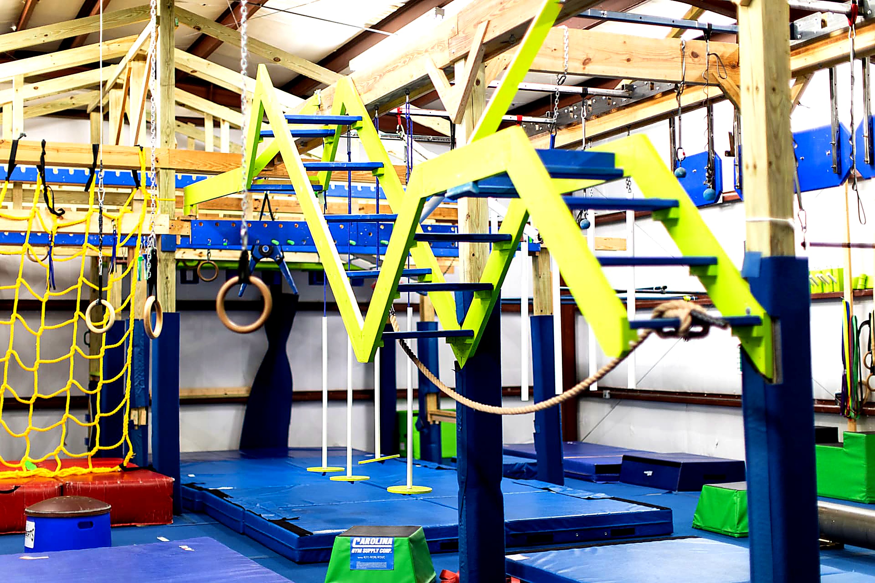 Green ninja peg ladders and rings on the obstacle rig