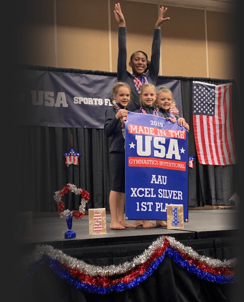 Elite Stars gymnasts holding an AAU Xcel Silver 1st place banner