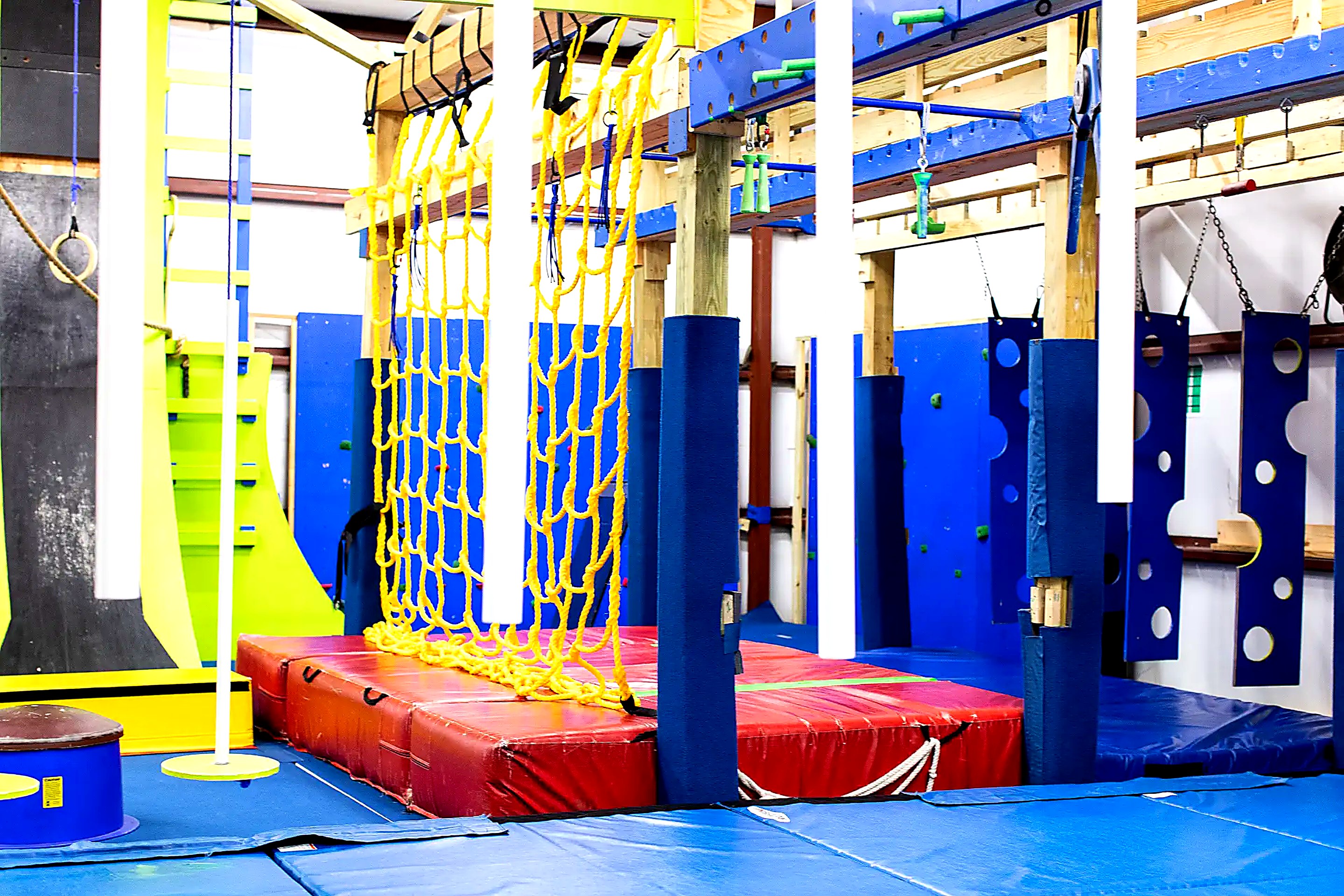 Cargo net climb over red landing mats in the ninja gym
