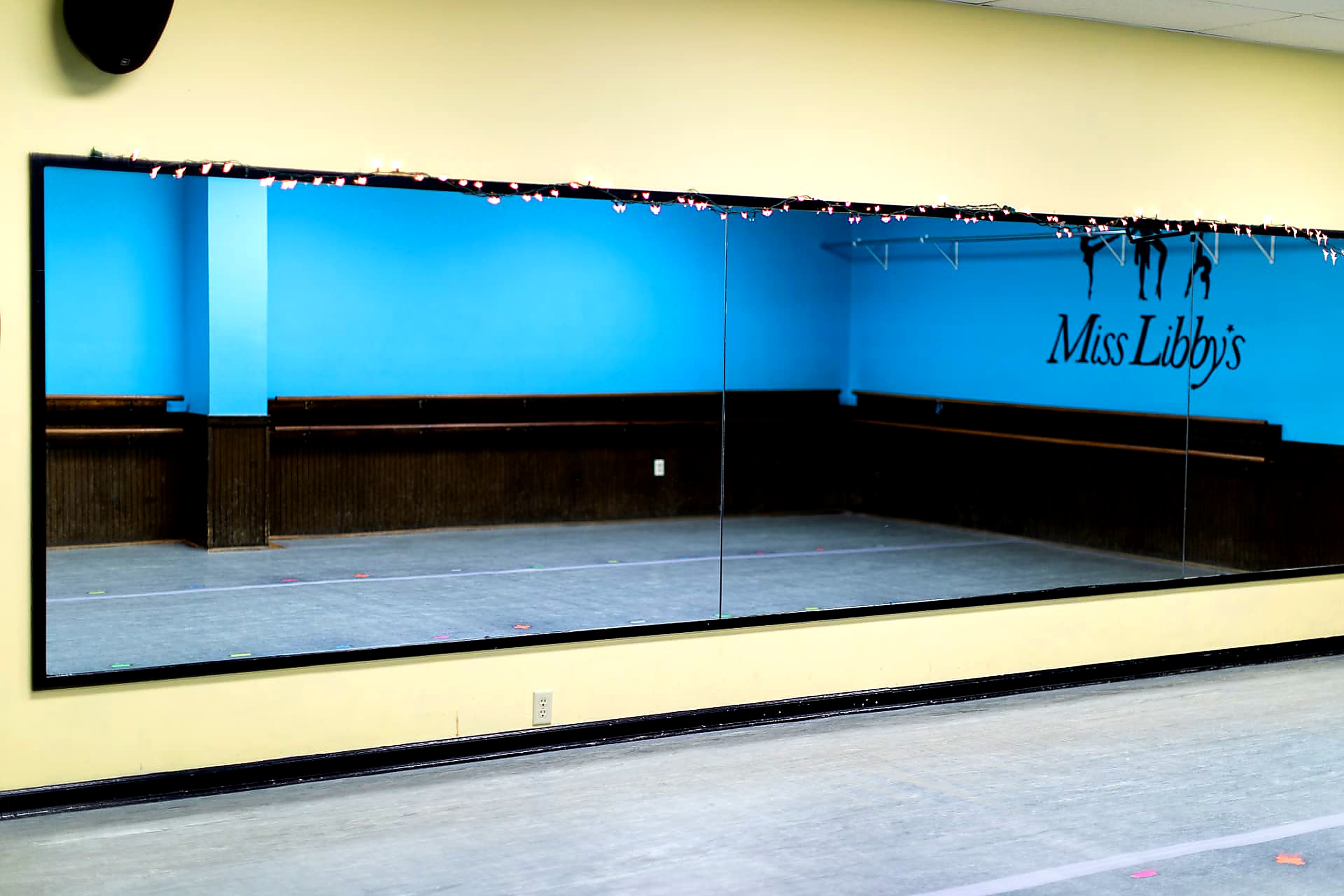 Full-length studio mirror reflecting the blue dance room