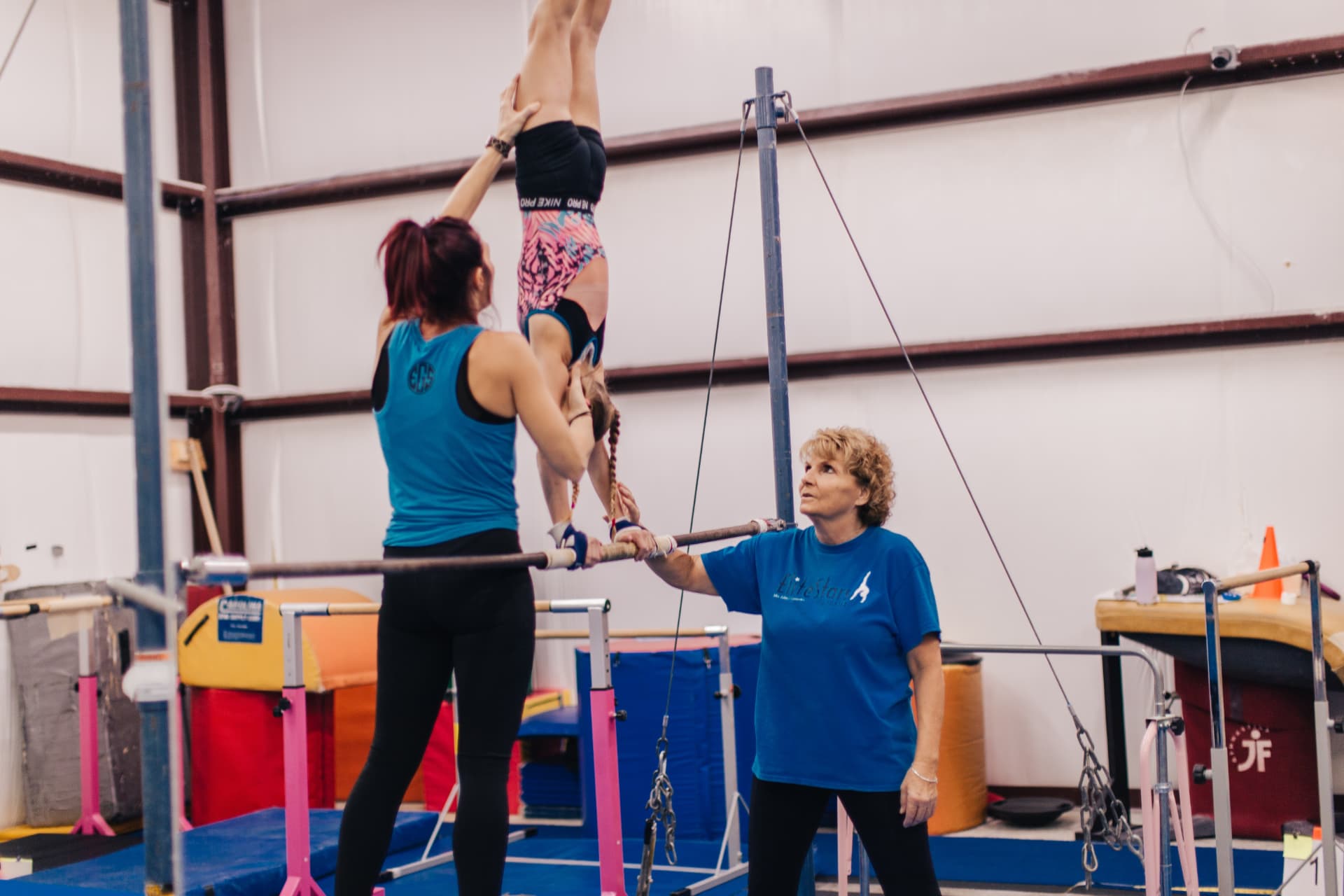 Elite Stars coaches spotting a gymnast on the bars