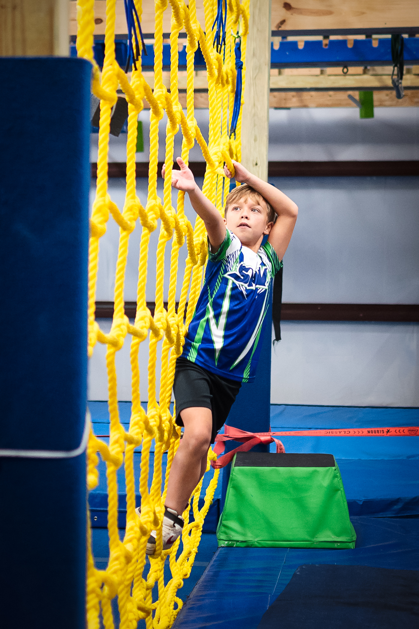 Young ninja athlete climbing the cargo net at Miss Libby's